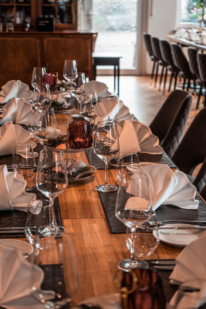 ours-journey A beautifully set dining table with fine flatware, wine glasses, and folded napkins.