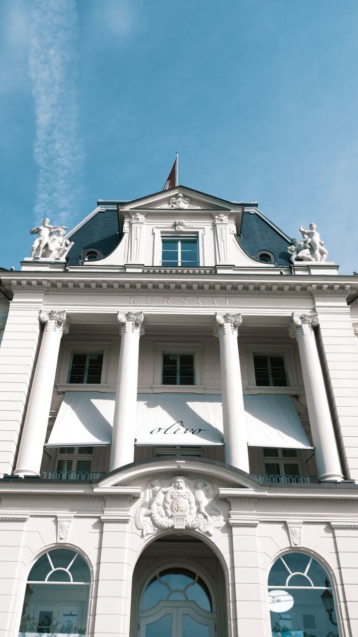 Front view of a neoclassical building with columns and sculptures under a clear sky.