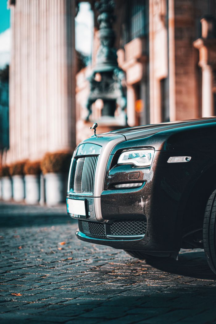 Close-up of a black Rolls Royce car parked on a city street, showcasing luxury design.